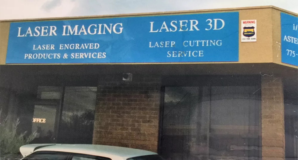 A shopfront with a sign reading "Laser imaging. laser engraved products & services. Laser 3D - Laser cutting service"
