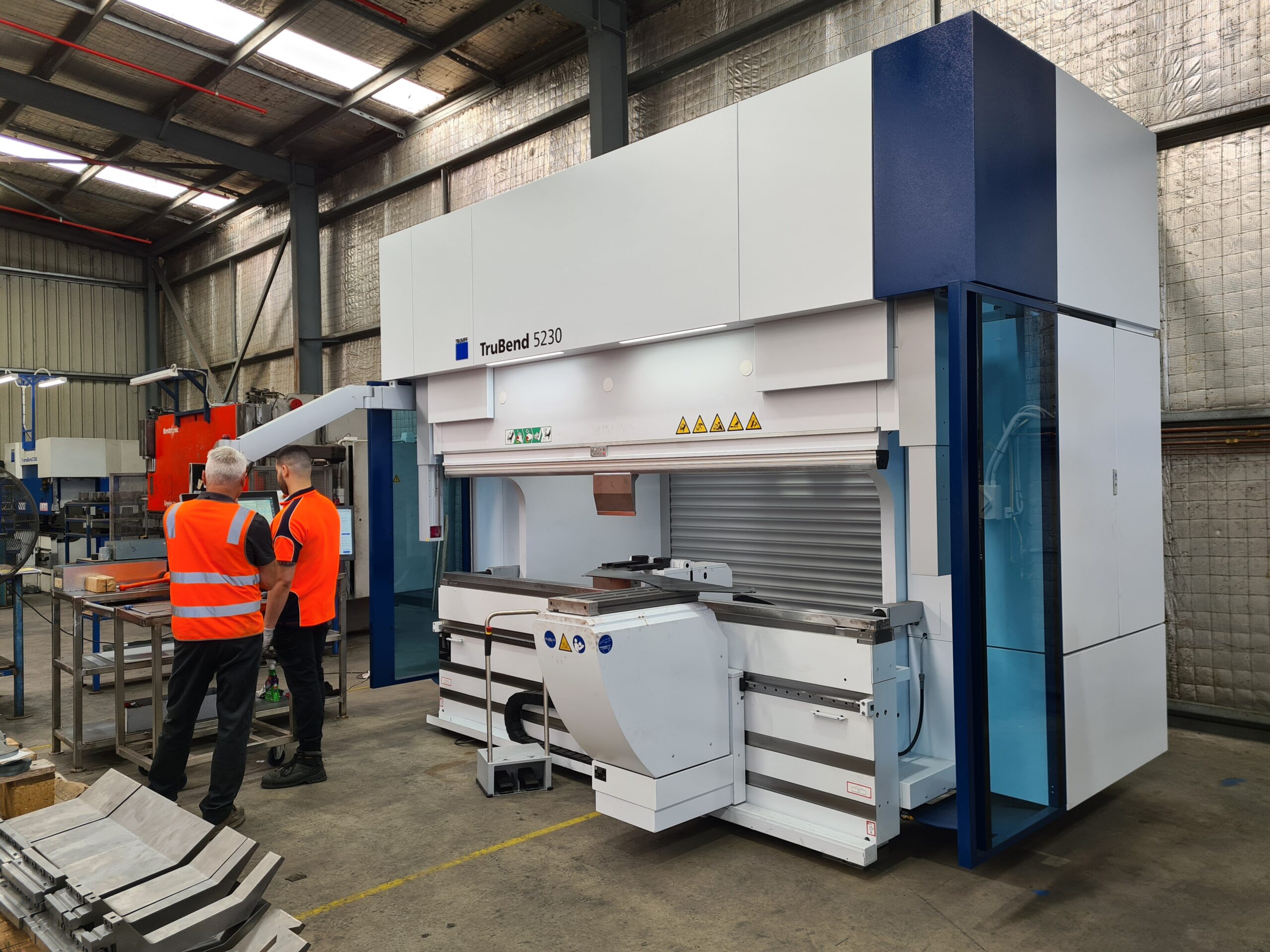 Laser 3D technicians operating advanced press brake machine for precision metal fabrication.